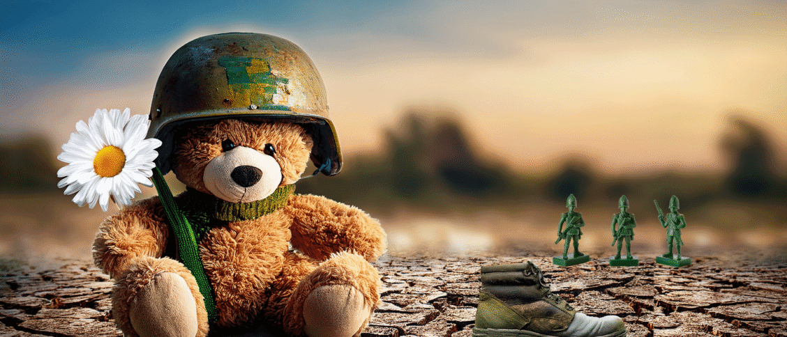 teddy bear wearing helmet, sitting on cracked earth, next to abandoned boots.